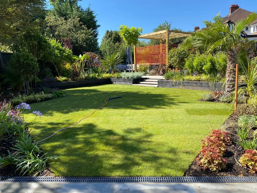 Beautiful back garden with rear pergola corner, mature planting and a manicured lawn